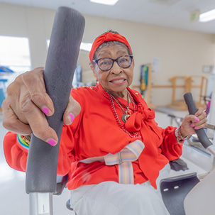 Senior woman in bright clothing, smiling and holding equipment.