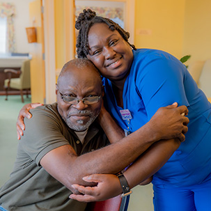 Smiling nurse and patient sharing a warm embrace.