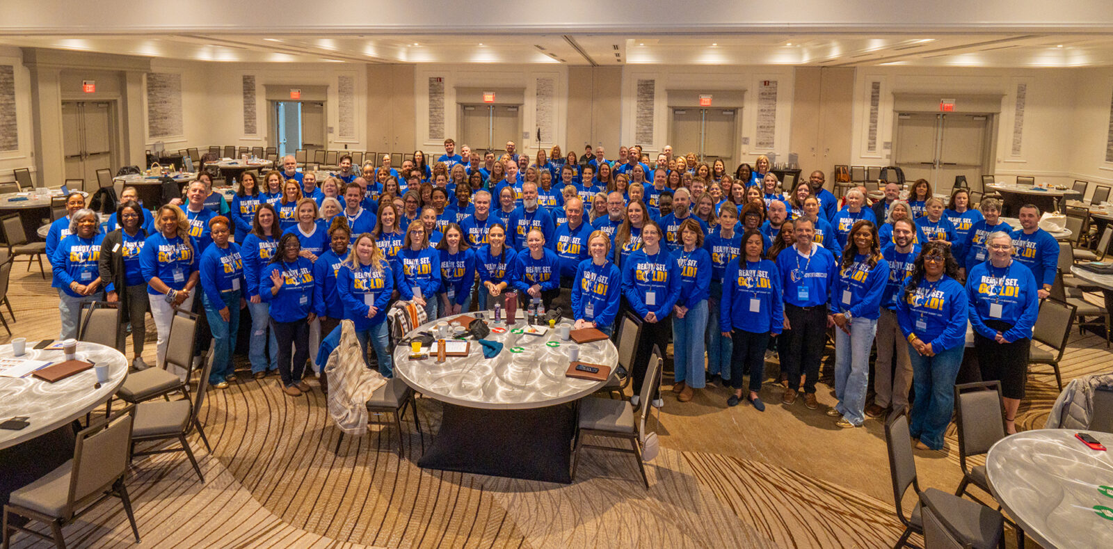 Group photo of people in blue shirts at an event.